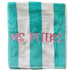 Turquoise and white striped beach towel with teacher name Ms. Peters embroidered in pink script